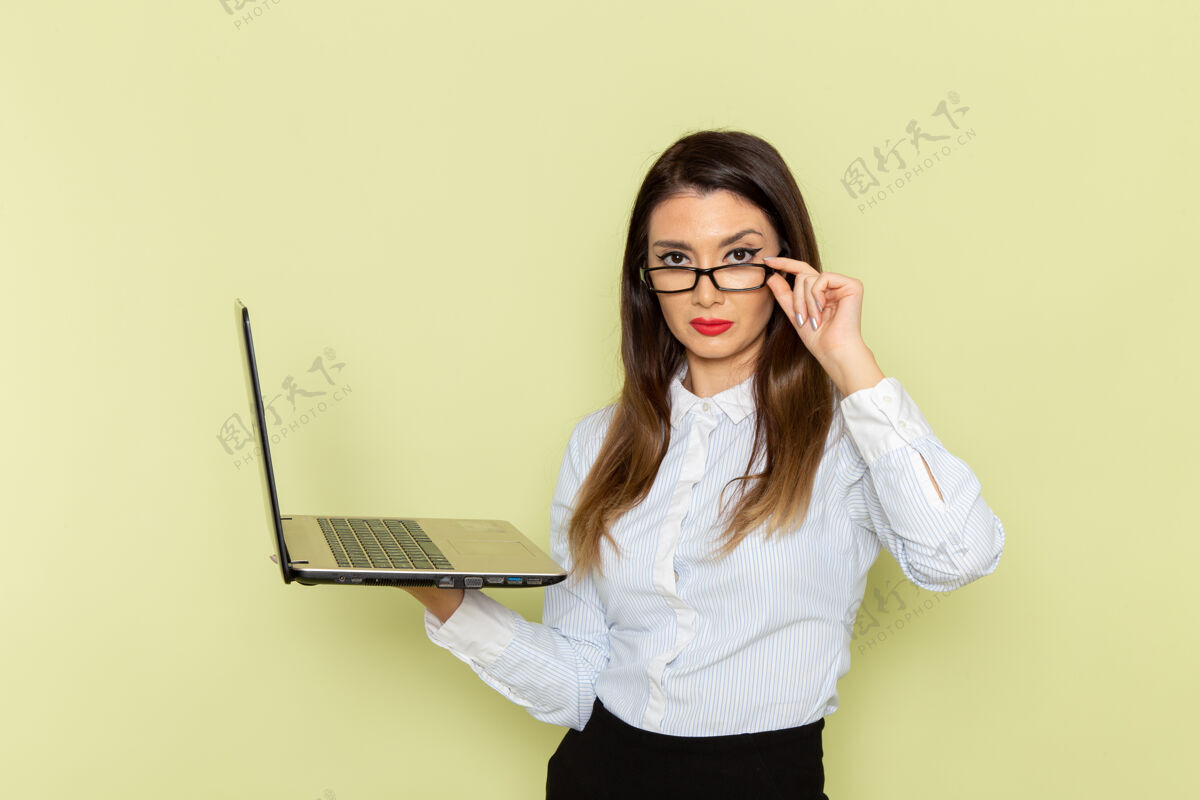 微笑穿着白衬衫和黑裙子的女上班族在绿墙上拿着笔记本电脑的正视图工作衬衫成人