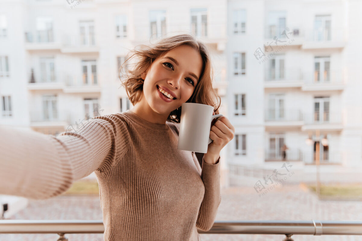 快乐美丽的微笑着的女人 端着一杯咖啡站在城市里积极的黑发女孩 一边喝茶一边享受着早晨室内肖像成人