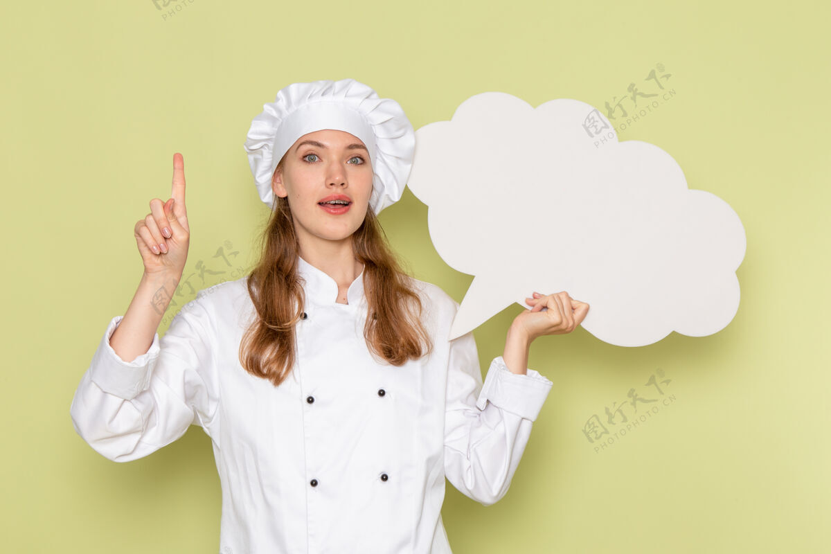 举行身穿白色厨师服的女厨师手持绿色墙上的白色标志的正面视图饭前面女