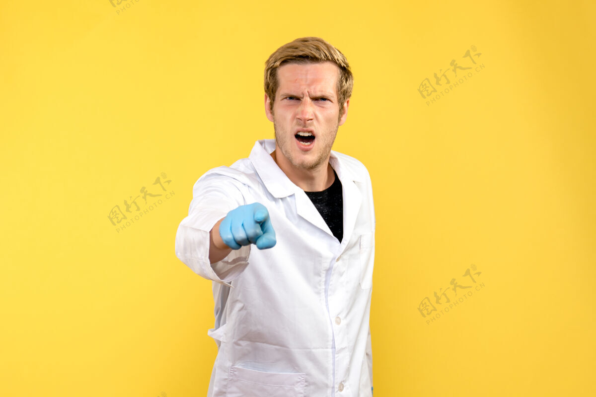微笑正面图黄色背景上一脸愤怒的男医生 医生大流行帅哥外套