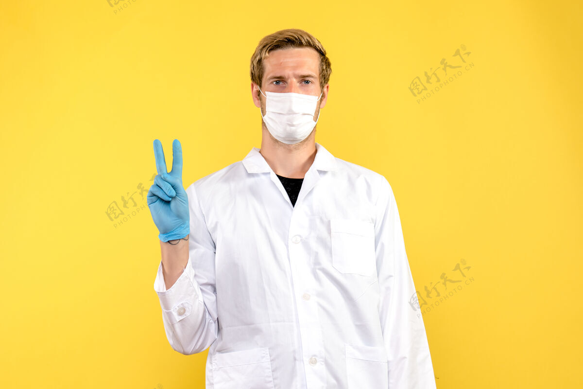 外套正面图黄色背景上戴着面罩的男医生-医疗大流行实验室人员医院