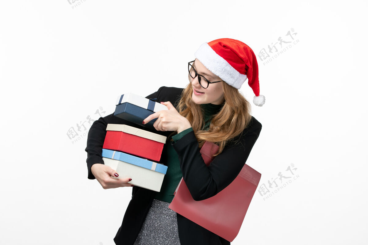 风景正面图年轻女性手持节日礼物放在白色书桌上礼物圣诞新年微笑工人年轻的女性