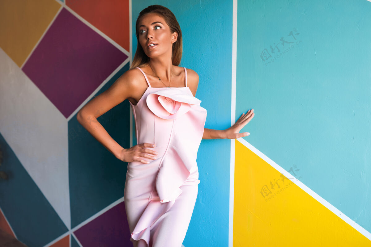 服饰穿着粉色连衣裙的娇嫩苗条的女人站在五颜六色的墙上时尚可爱女性