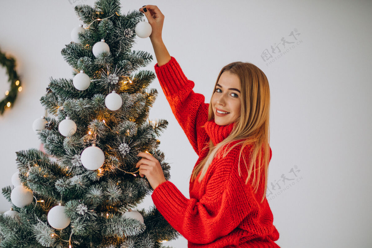 女性装饰圣诞树的年轻女人庆祝时尚圣诞树