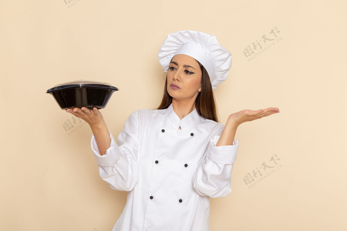 专业身穿白色厨师服的年轻女厨师在白墙上拿着平底锅的正视图年轻套装厨房