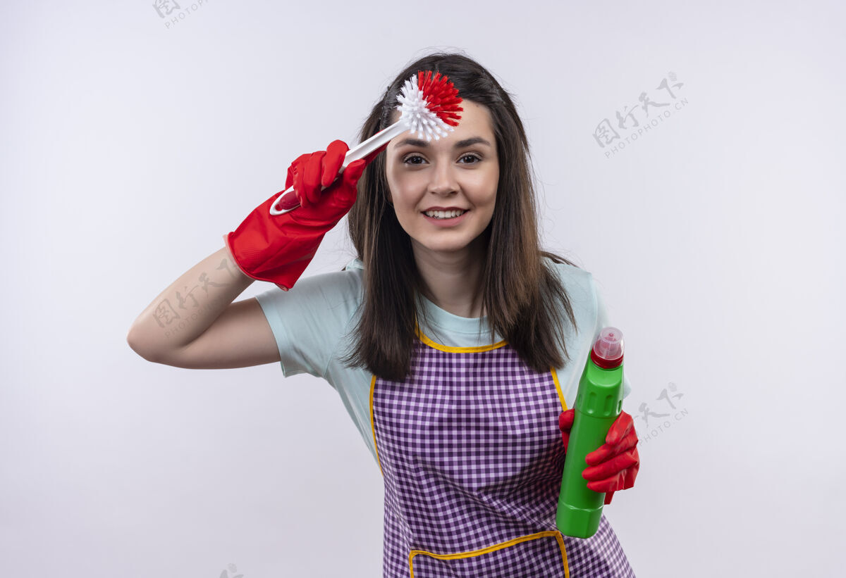 东西年轻漂亮的女孩穿着围裙 戴着橡胶手套 手里拿着清洁用品和刷子 远远地用手捂着头看东西供应刷子头