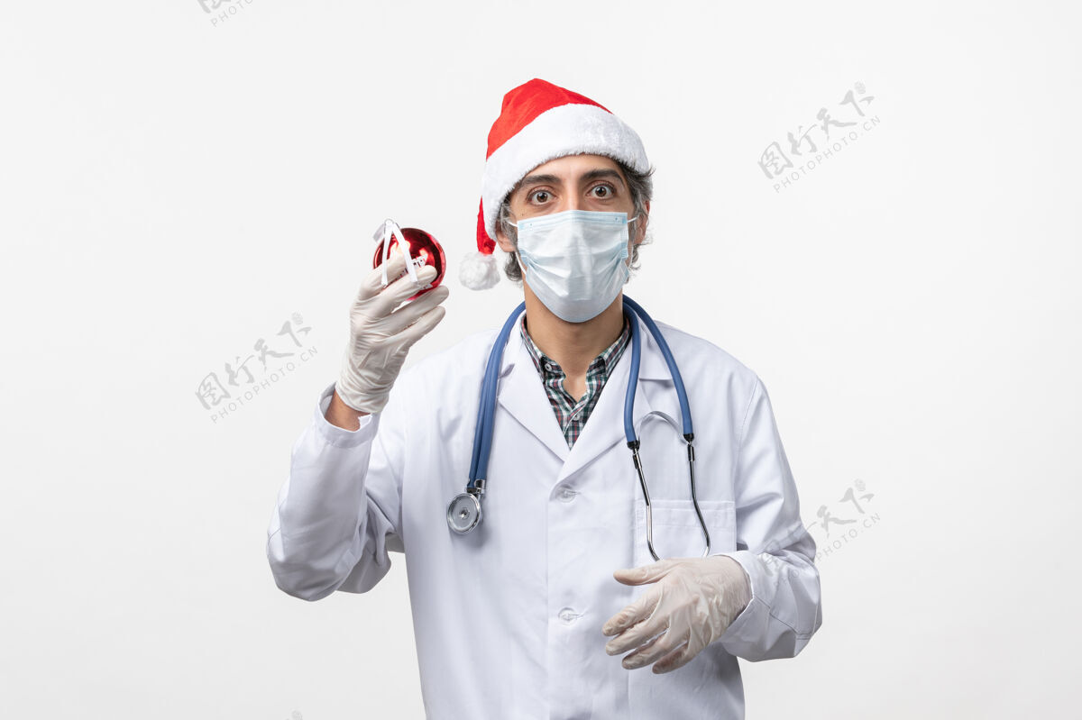 医院正面图白壁上有新年树玩具的男医生病毒健康病毒男人视图制服