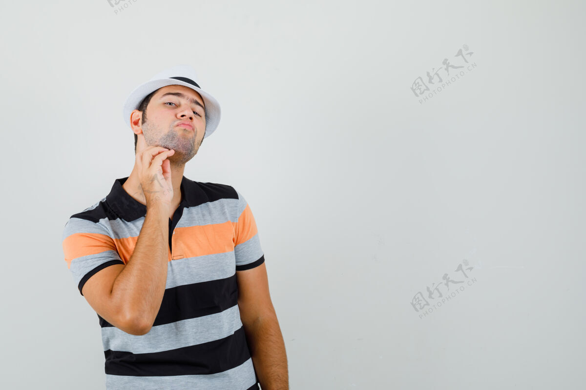 休闲一个穿着t恤 戴着帽子的年轻人刮着胡子 在一个安静的空间里寻找文字抓挠男帽子
