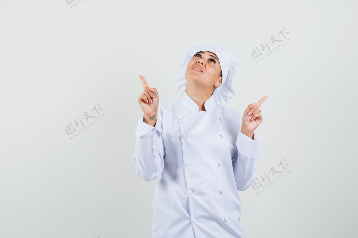 服务一位身穿白色制服的女厨师向上指了指 看上去很专注烹饪集中餐厅