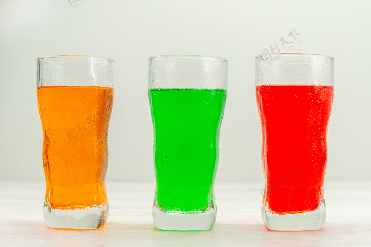 玻璃杯正面图白色表面上的长玻璃杯内五颜六色的果汁生的鸡尾酒啤酒杯