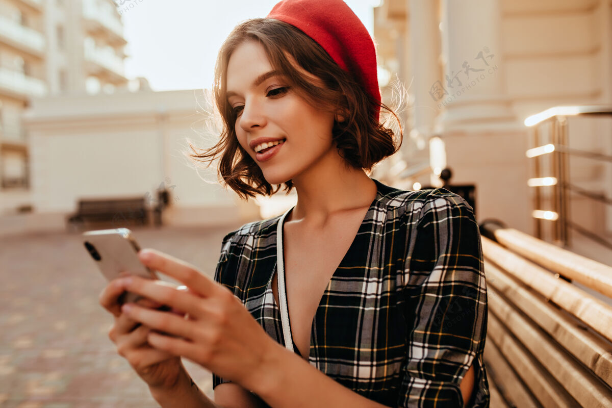 快乐秋日里 温文尔雅的女孩在发短信戴着红色贝雷帽的温文尔雅短发女人拿着手机站在街上户外电话街道