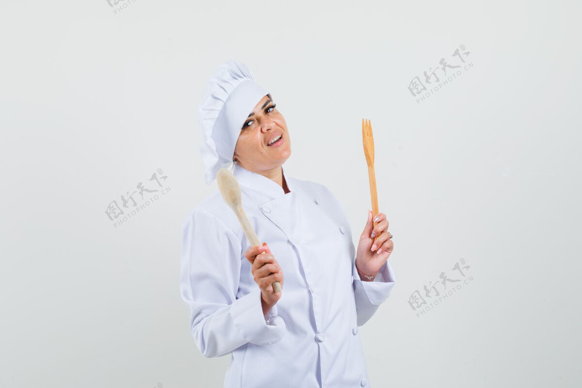 工人女厨师手拿木勺和叉子 穿着白色制服 看上去很自信工作烹饪举行