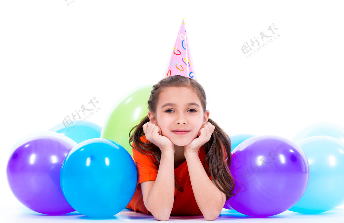 情感穿着橙色t恤的快乐微笑女孩躺在地板上 带着五颜六色的气球-孤立在白色的地板上乐趣女性美丽