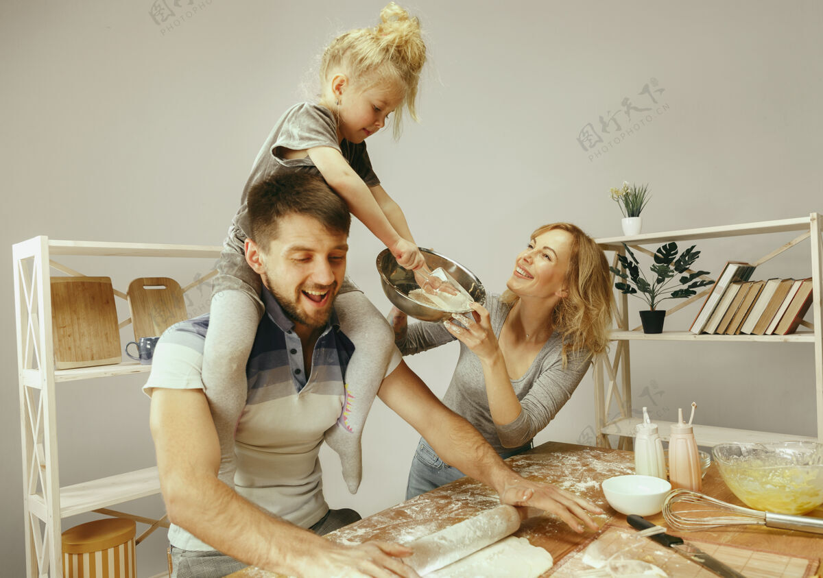 男性可爱的小女孩和她美丽的父母在家里的厨房里为蛋糕准备面团孩子可爱休闲