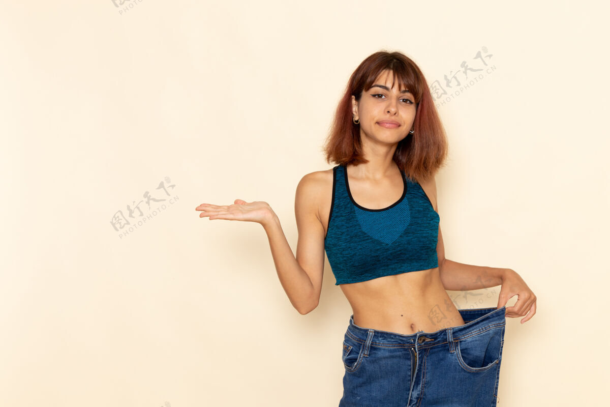 漂亮年轻女性穿着蓝色衬衫 身体健康 在浅白的墙上微笑身体锻炼运动