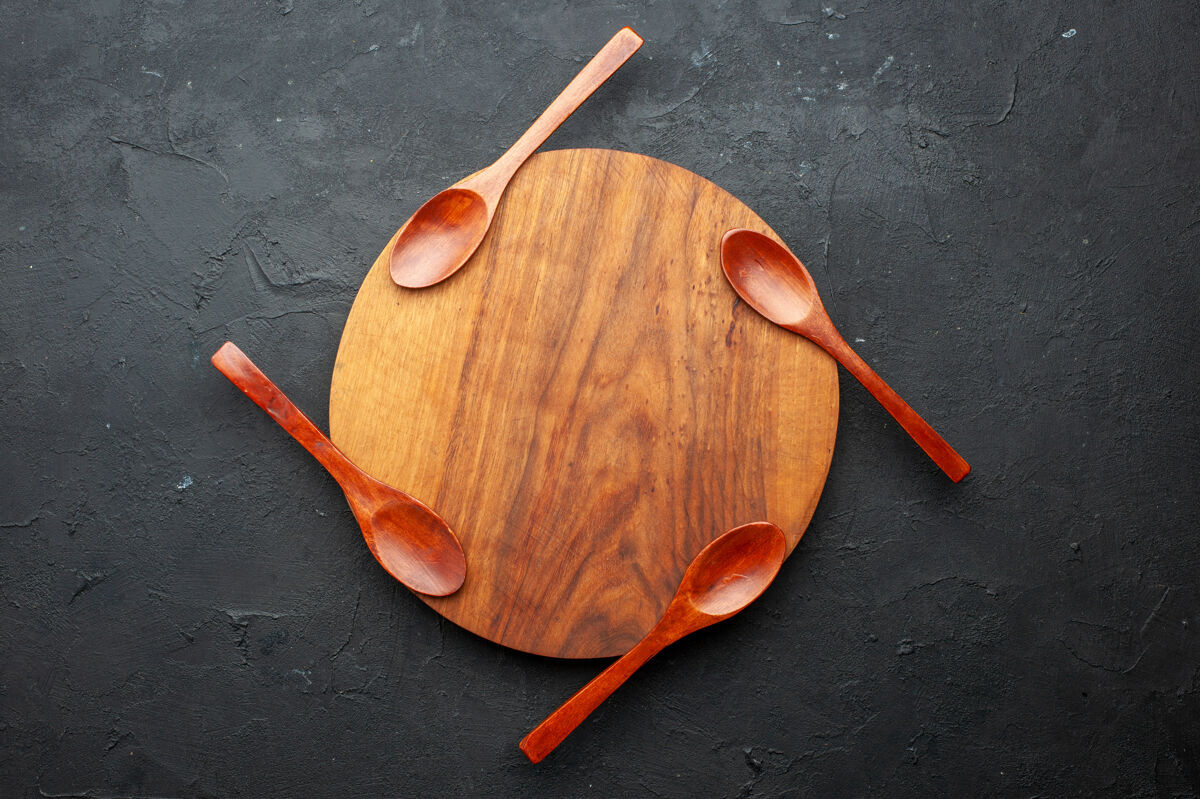 木板顶视图四个勺子放在黑色桌子上的圆木板上 有复印空间木头勺子圆的