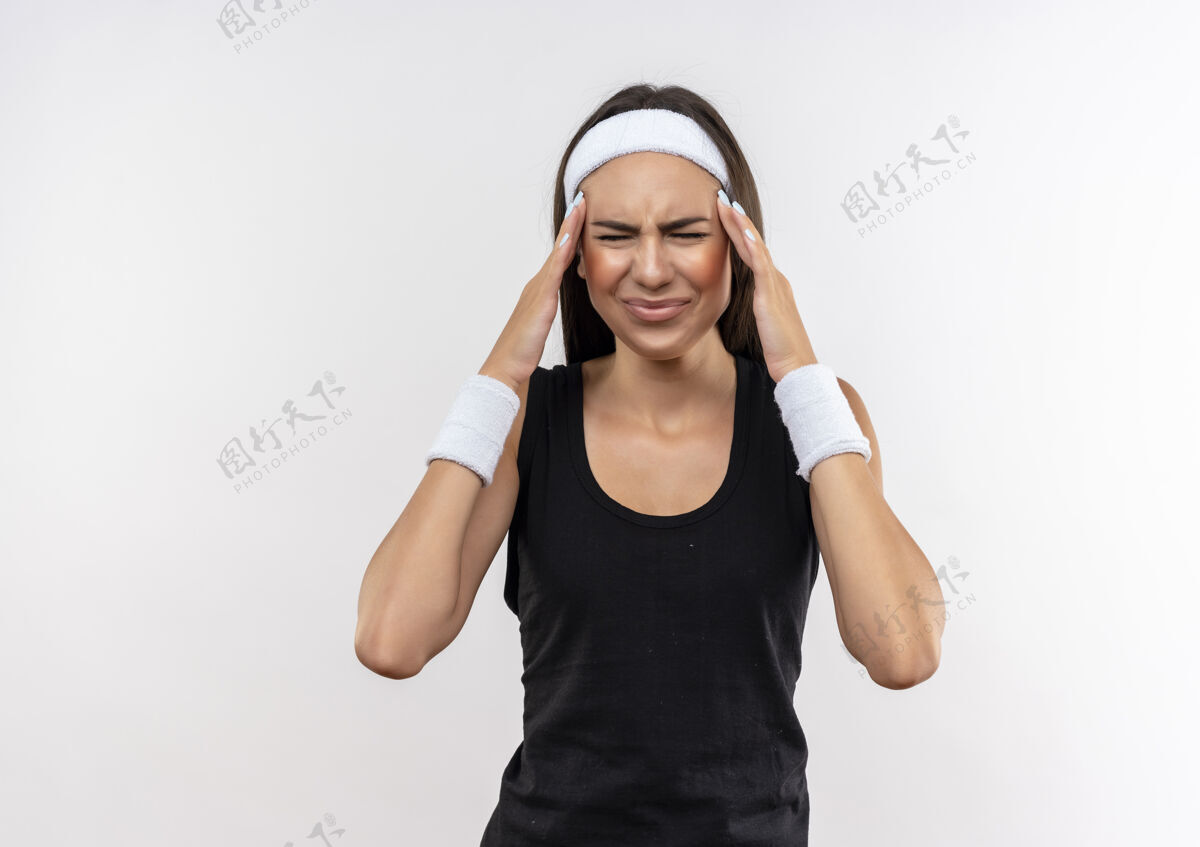头有压力的漂亮运动女孩戴着头带和腕带把双手放在头上闭着眼睛隔离在白色空间放眼睛穿