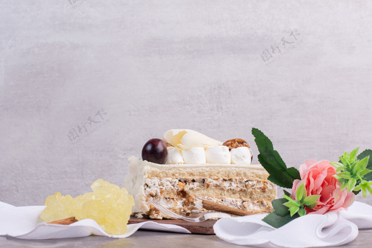 一块大理石桌上有白巧克力蛋糕和糖果和鲜花蛋糕自制奶油