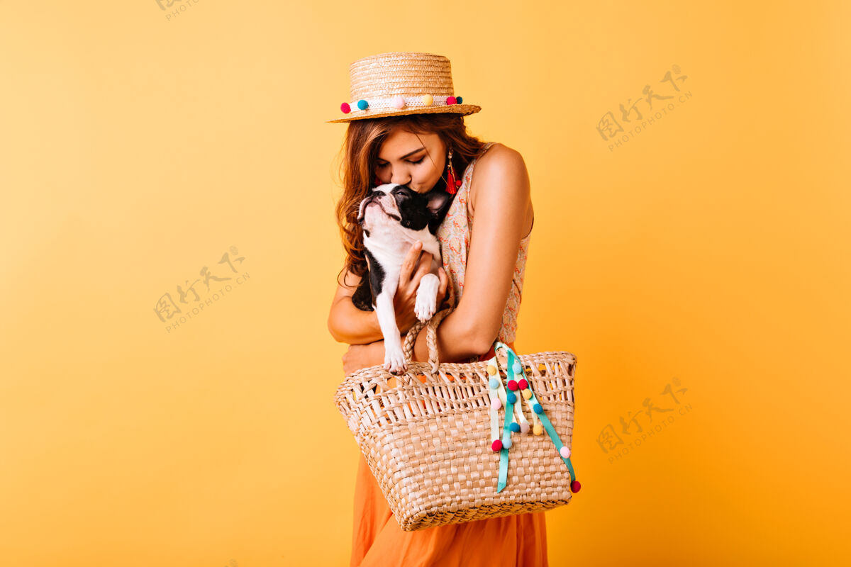 休息可爱的女孩戴着草帽亲吻她的狗时髦的姜黄色女人和小狗摆姿势放松女性人