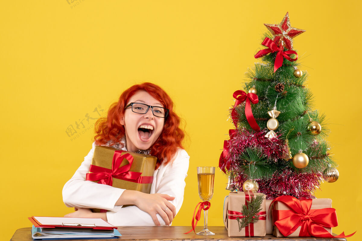 插花前视图女医生坐在黄色背景上与圣诞礼物礼物前面情感