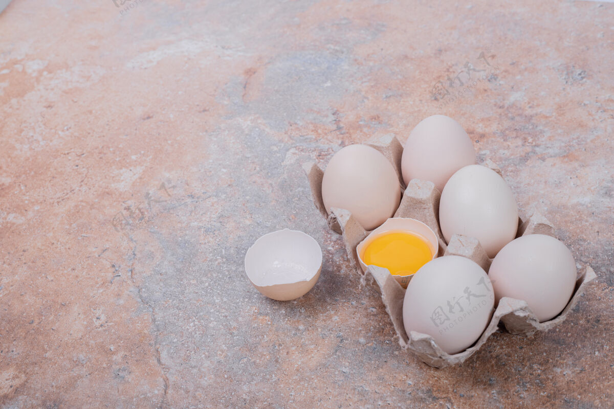 破碎鸡蛋放在大理石表面的纸容器里生的生的新鲜