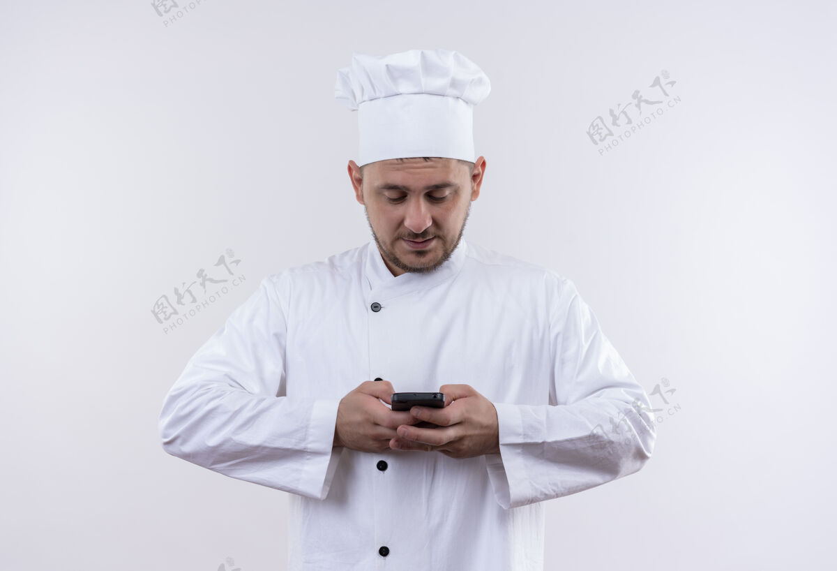 手持年轻帅气的厨师手拿着厨师制服 用手机隔离在空白处制服年轻高兴