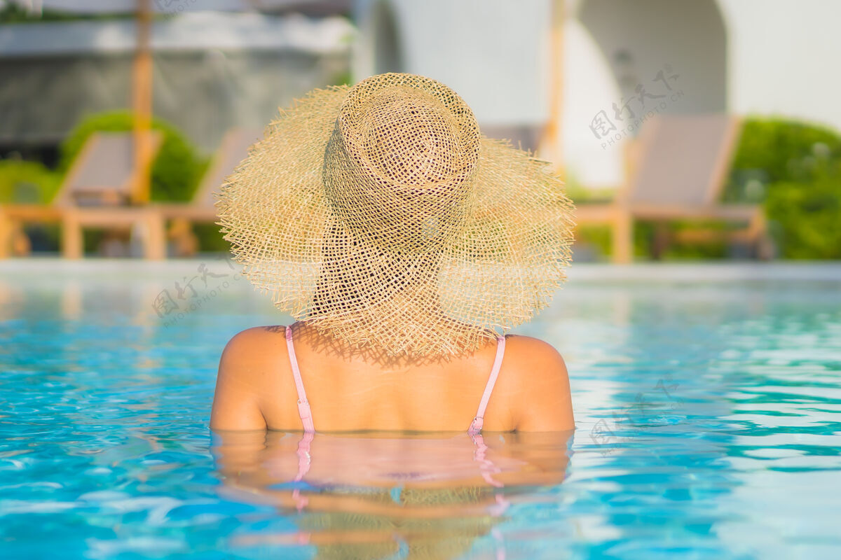 亚洲肖像美丽的亚洲年轻女子放松休闲围绕室外游泳池与海身体健康度假