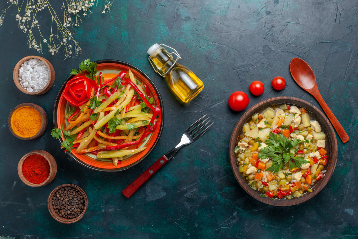 辣椒在深蓝色背景上 可以俯瞰不同调味料的蔬菜汤和辛辣沙拉沙拉汤胡椒
