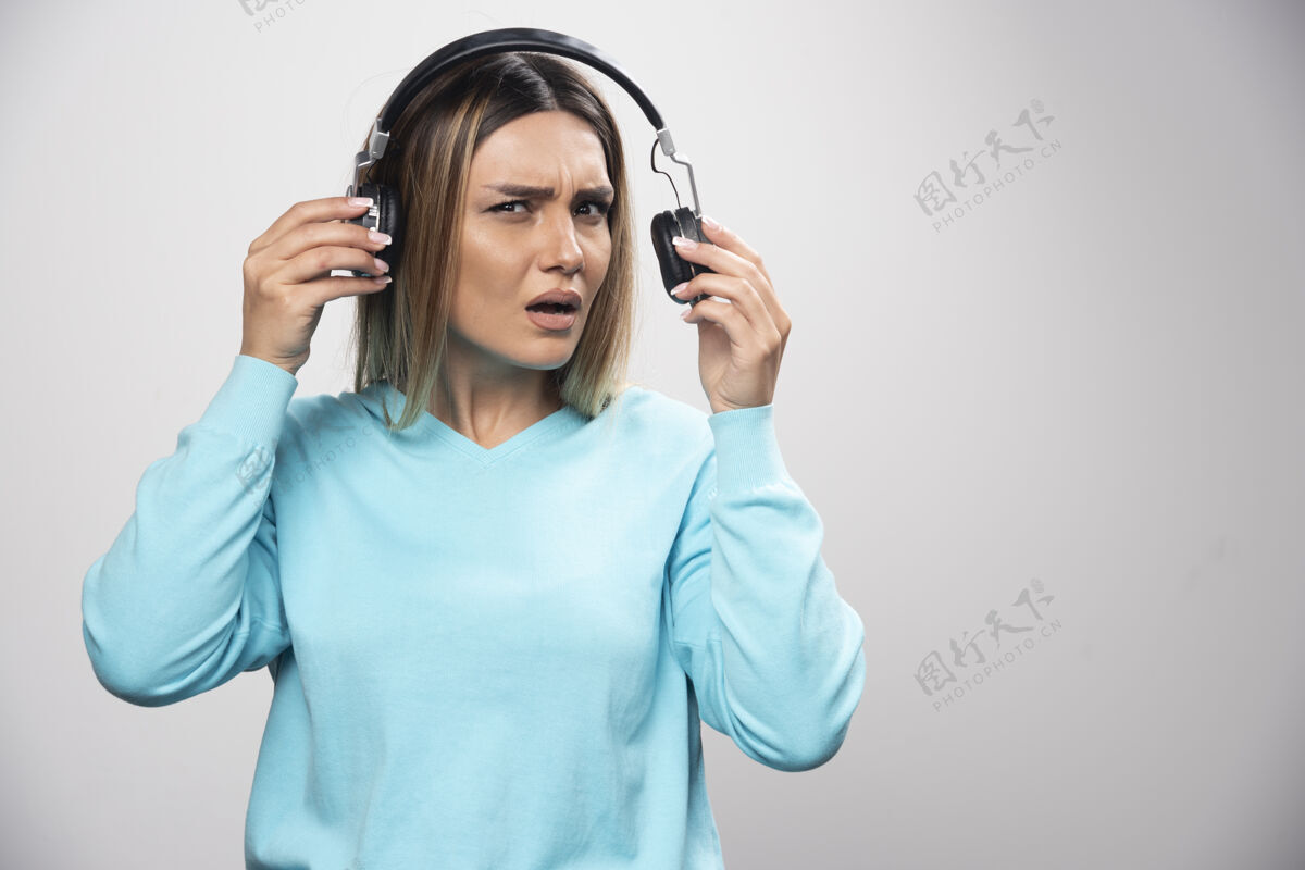 表演穿着蓝色运动衫的金发女孩听着耳机 不喜欢音乐娱乐Dj员工