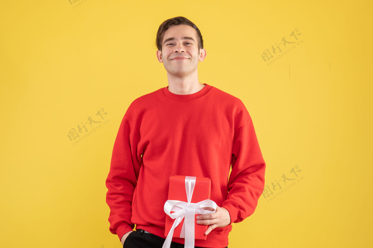 青春期正前方 一个穿着红毛衣的年轻人微笑着站在黄色的地板上专业毛衣休闲