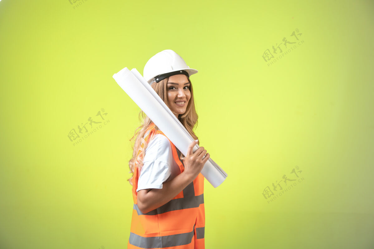 工作戴着头盔和装备的女工程师拿着施工图微笑着自信公司专业