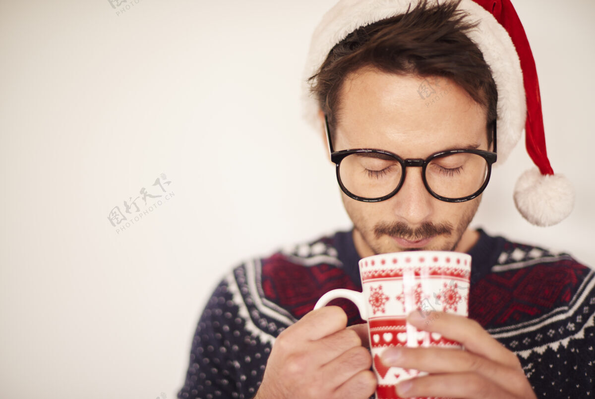 眼睛闭上戴圣诞帽的男人在喝热巧克力圣诞老人男人装饰