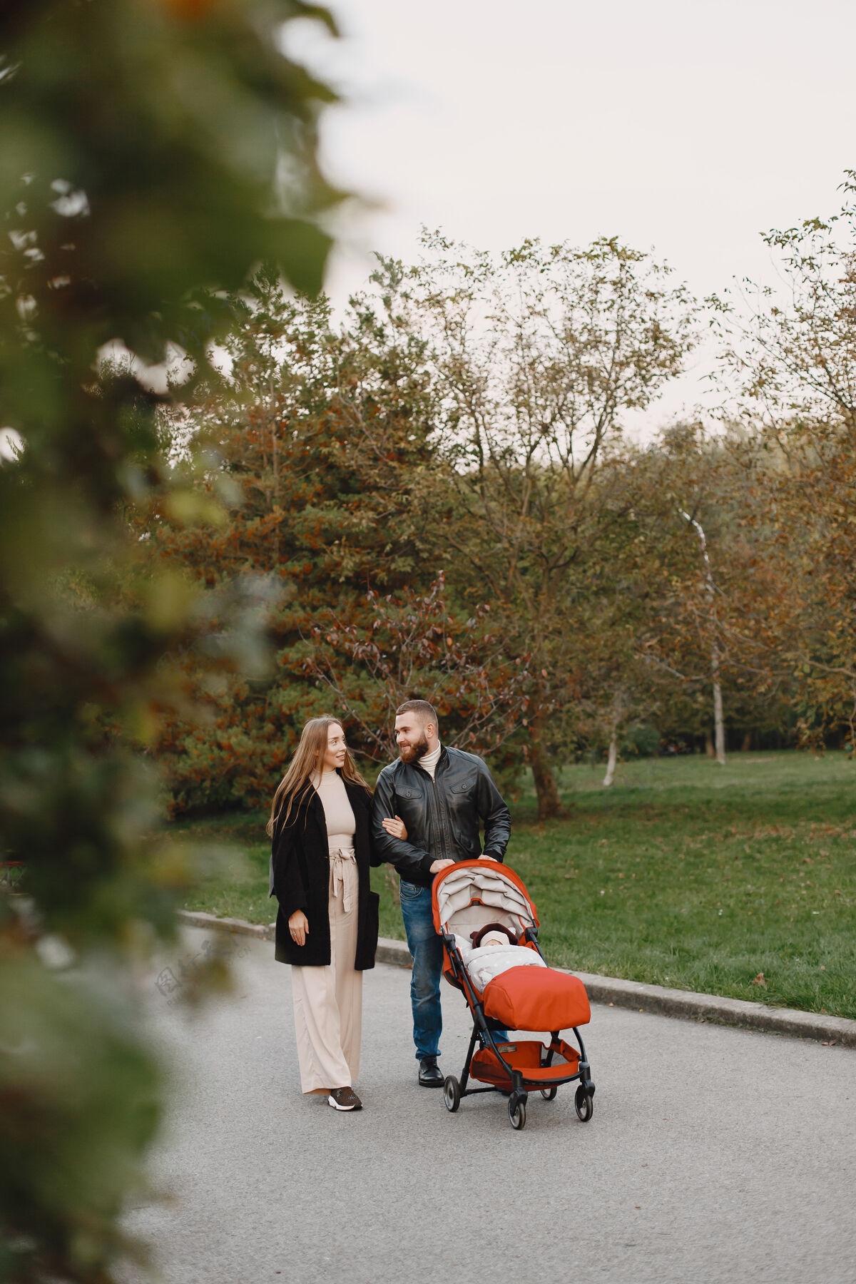 户外一家人在秋天的公园里男人穿着黑色夹克可爱的小女孩和父母女性马车聚在一起