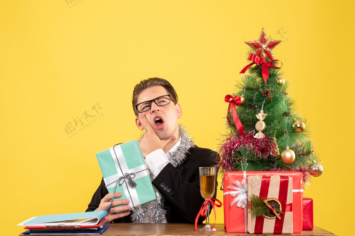 坐正面图：男工人拿着圣诞礼物坐着圣诞节年工作