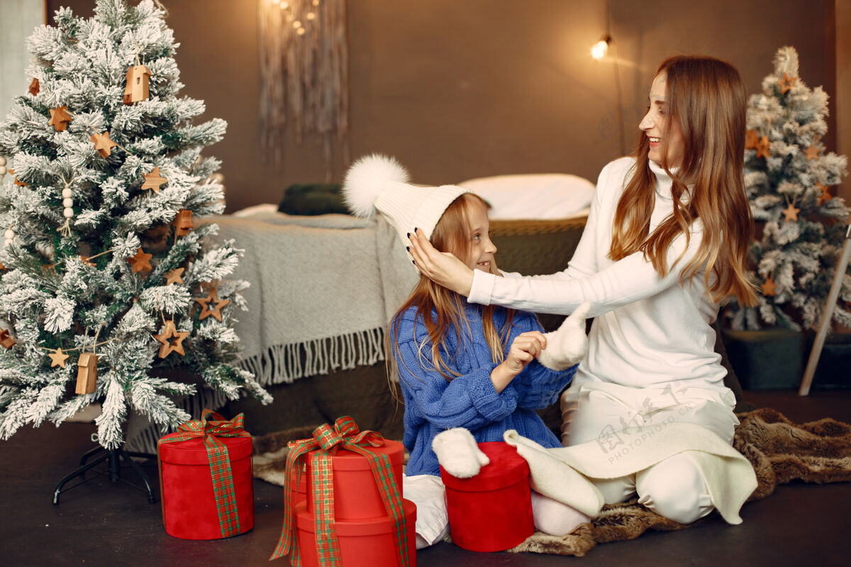 母亲人们在为圣诞节做准备母亲在和女儿玩耍一家人在节日的房间里休息孩子穿着蓝色毛衣快乐礼物装饰