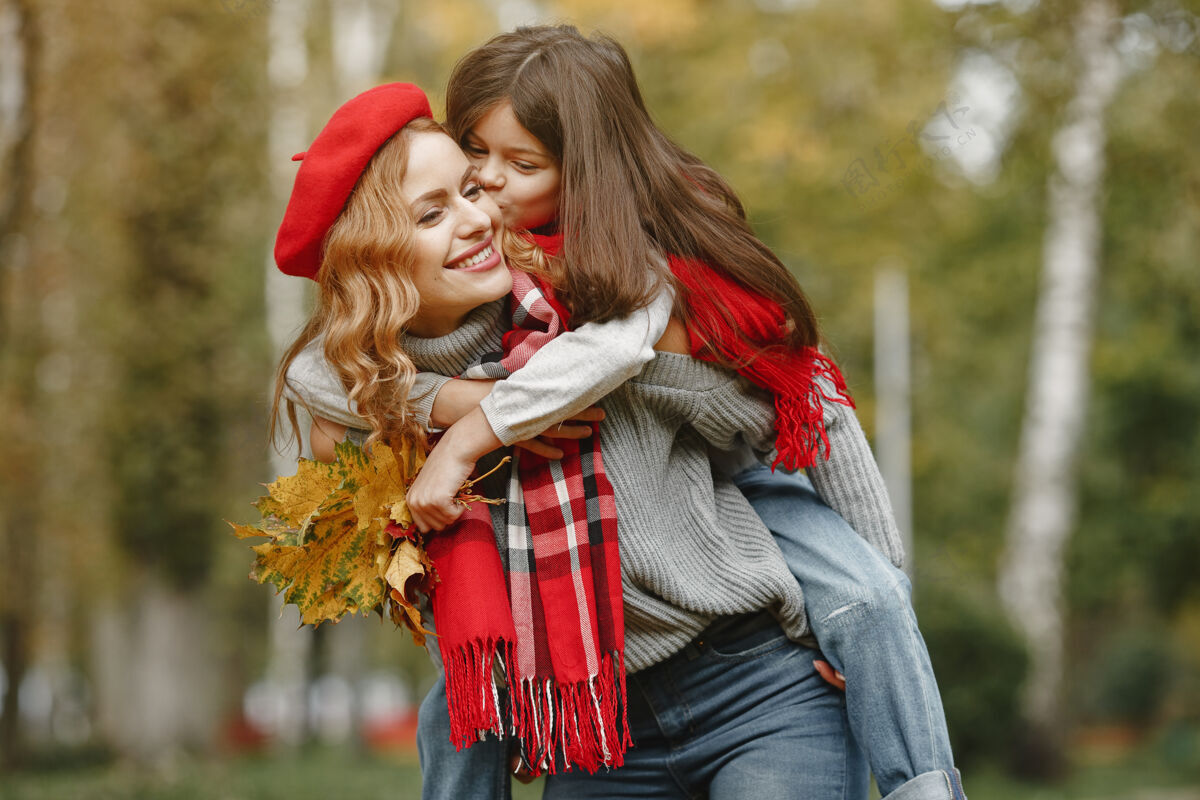 玩耍时髦的母亲带着女儿黄色的秋天戴着红领巾的女人休闲围巾肖像