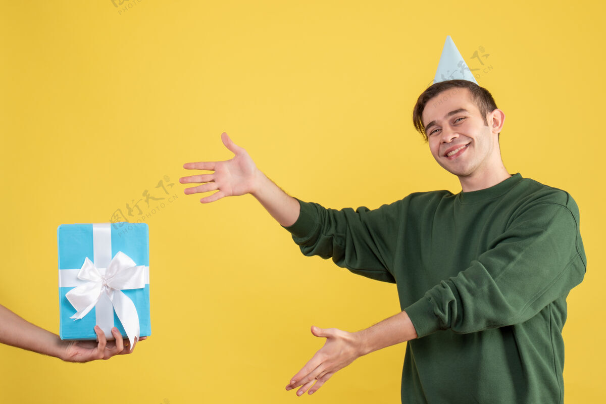 年轻正面图幸福的年轻人指着黄色的人手里的礼物礼物男人成人