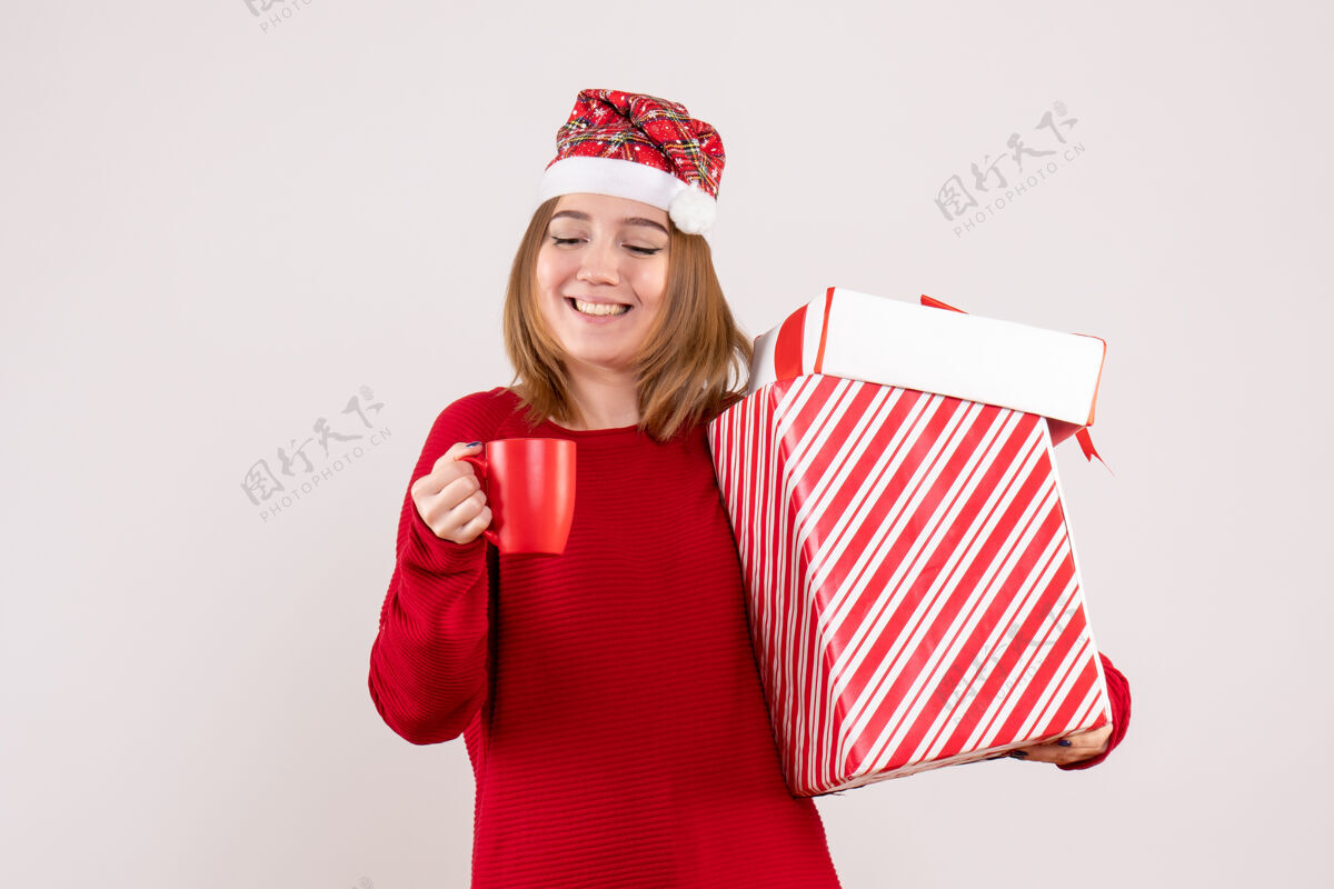 年带着礼物和一杯茶前视年轻女性年轻的女人帽子圣诞节