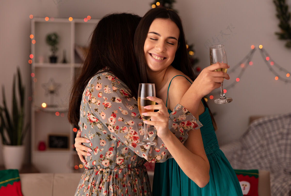 年轻快乐的年轻女孩们互相拥抱 捧着香槟 在家里享受圣诞节时光圣诞节每一个拥抱