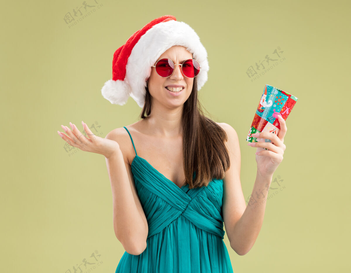 举行戴着太阳眼镜 戴着圣诞帽 手里拿着纸杯的年轻白种人女孩纸复制帽子