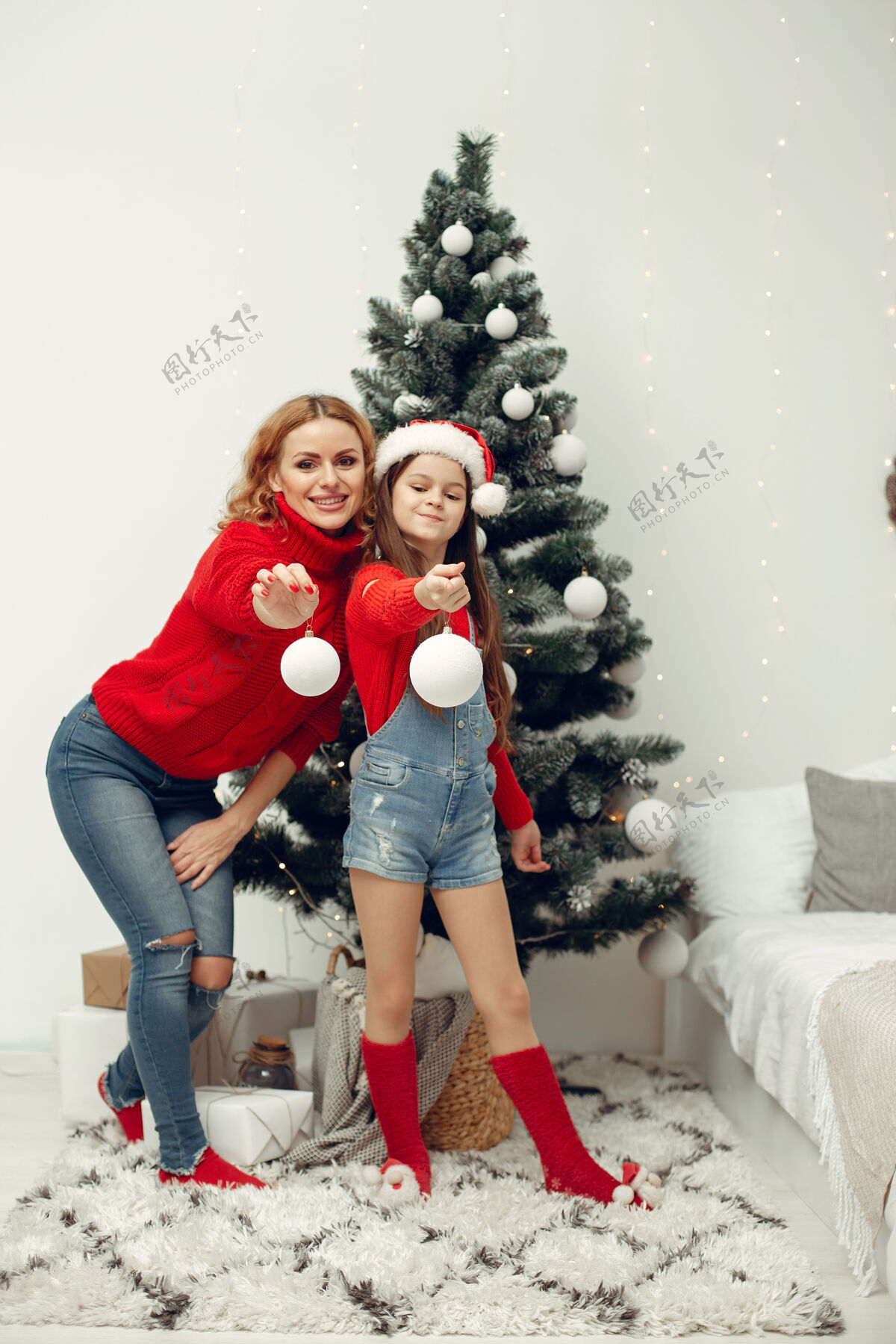 传统人们在为圣诞节做准备母亲在和女儿玩耍一家人在节日的房间里休息孩子穿着红色毛衣母亲帽子给予