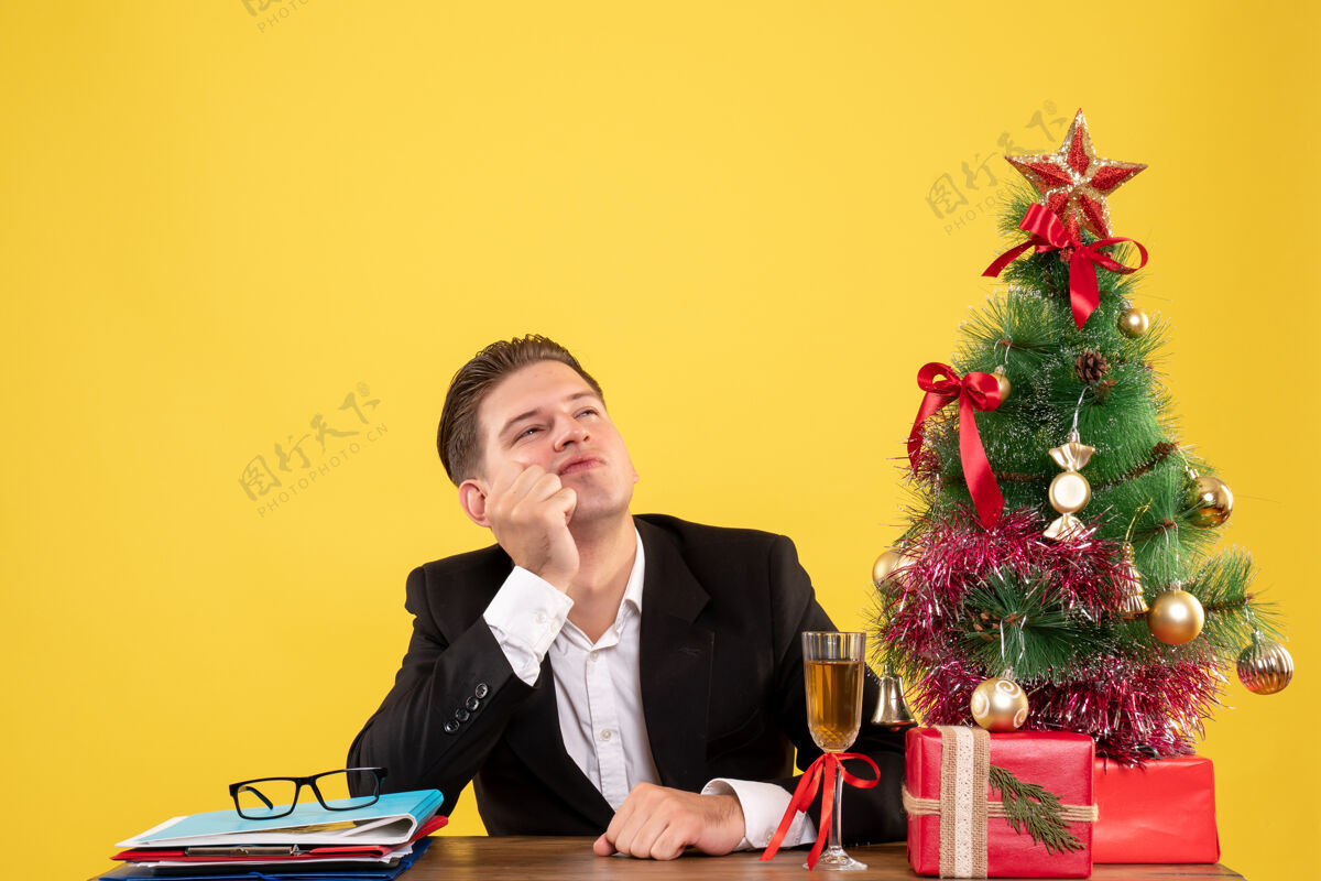 年轻的男工人前视图年轻的男工人坐在圣诞礼物和圣诞树颜色年份圣诞树