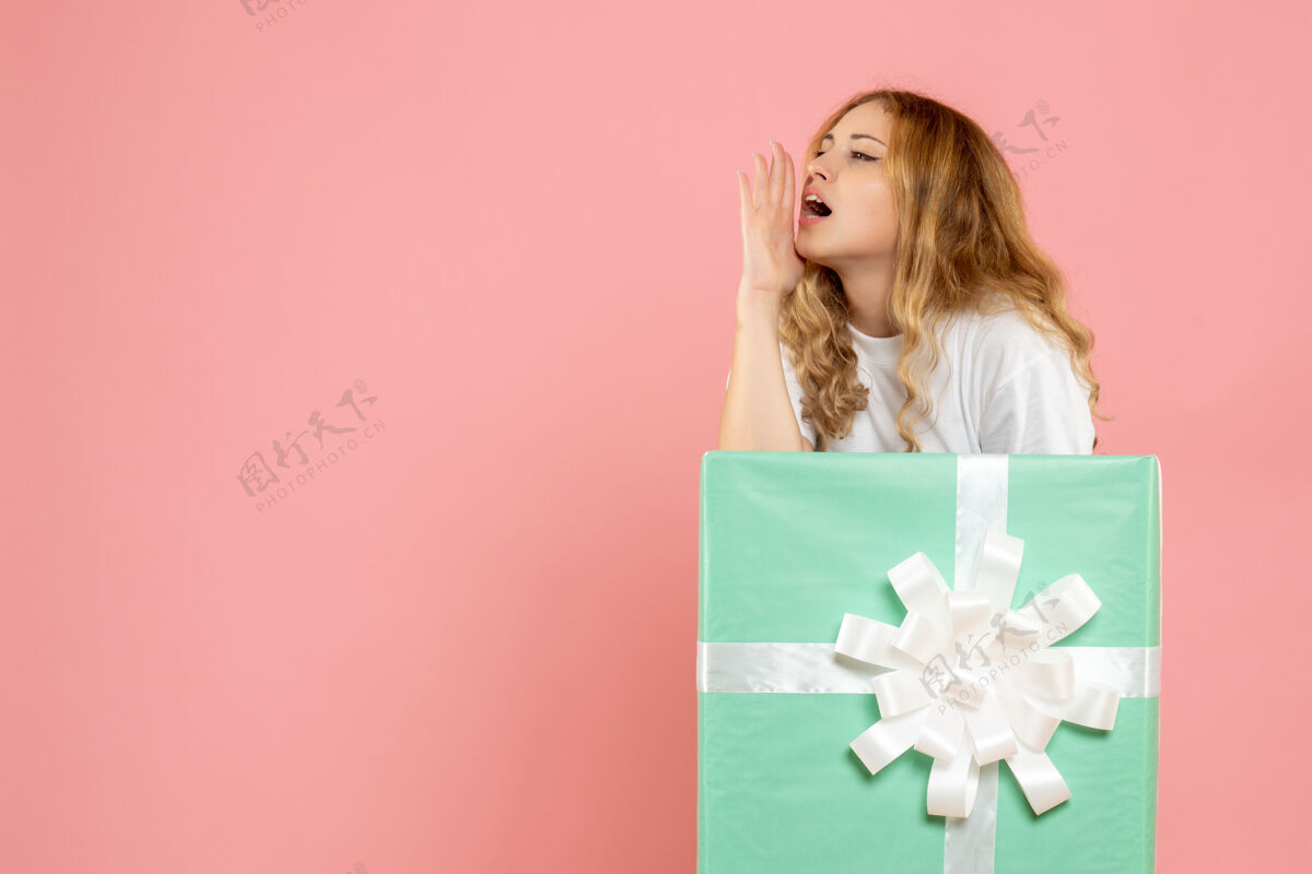 蓝色正面图蓝色礼品盒内的年轻女性在呼唤圣诞呼叫里面