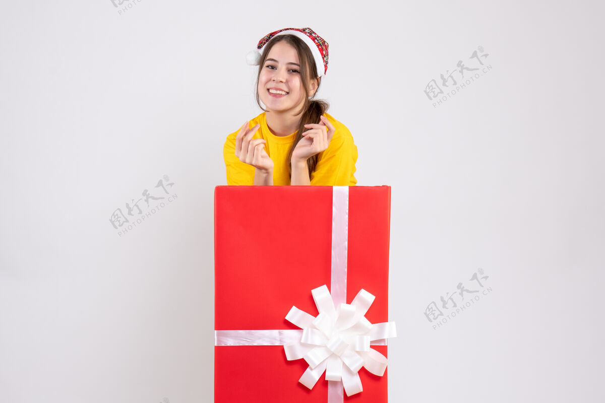圣诞老人戴着圣诞帽的快乐女孩站在白色圣诞礼物后面快乐女孩帽子