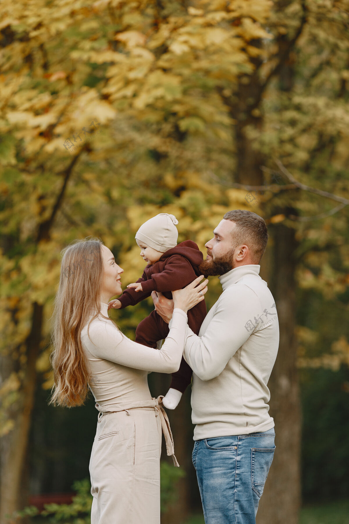 户外秋天公园里的一家人穿棕色毛衣的男人和父母在一起的可爱小女孩公园小男人