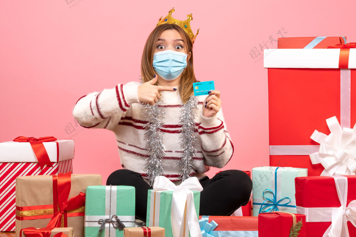卡片正面图：年轻女性拿着银行卡围坐在圣诞礼物旁年份节日坐着