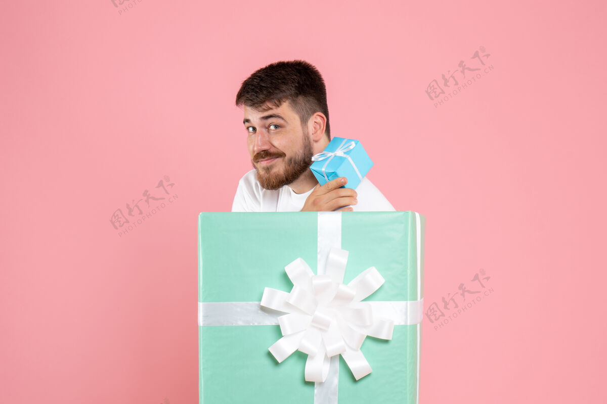 情感礼物盒内的年轻人的正面图 粉红色的墙上挂着小礼物年轻粉色礼物