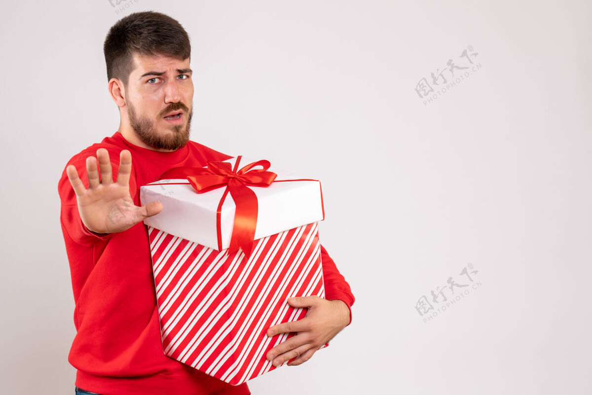 快乐身穿红衫的年轻人在白色墙上的盒子里拿着圣诞礼物节日前面圣诞