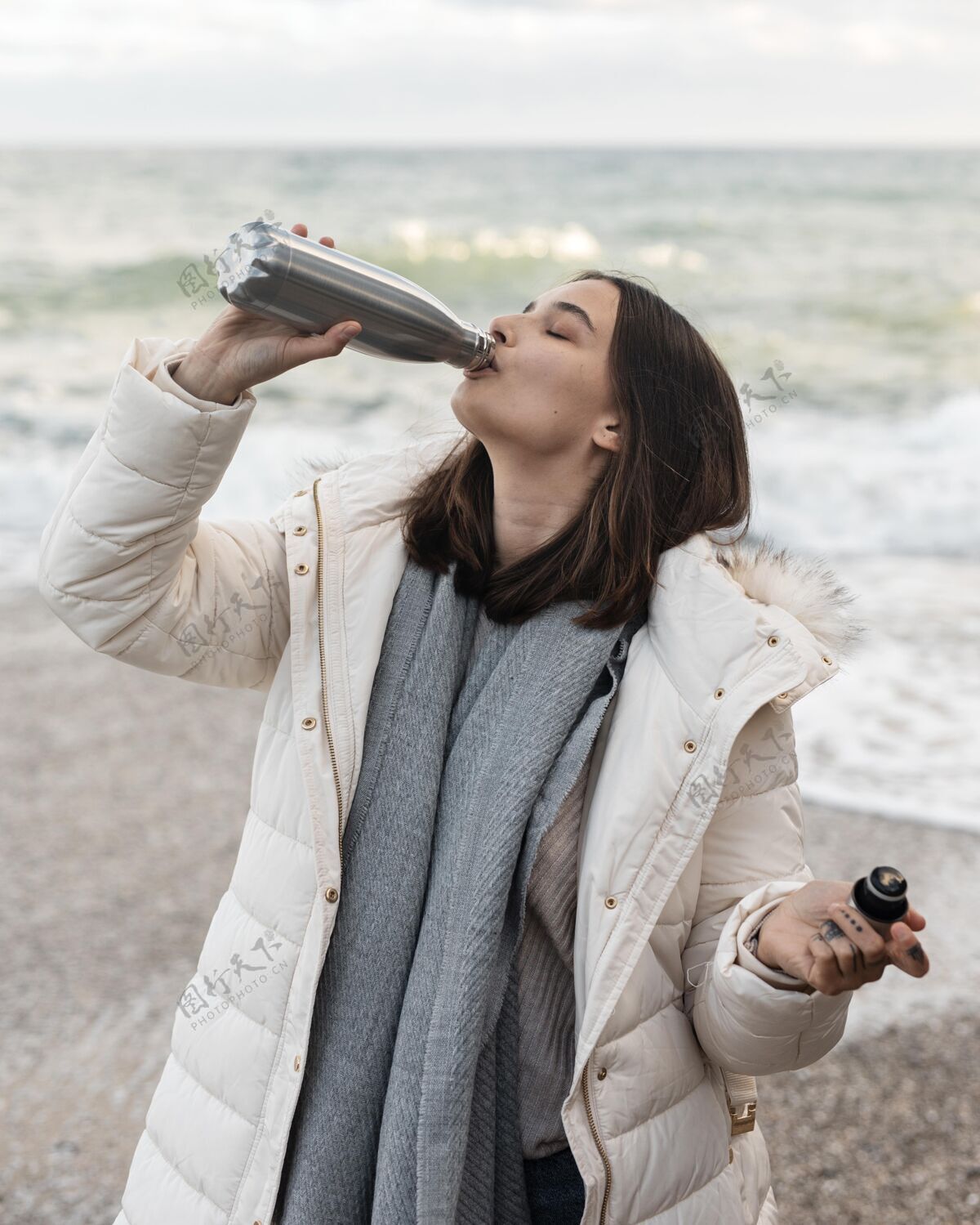 路海滩上的女人在喝瓶子里的酒公路旅行旅行瓶子