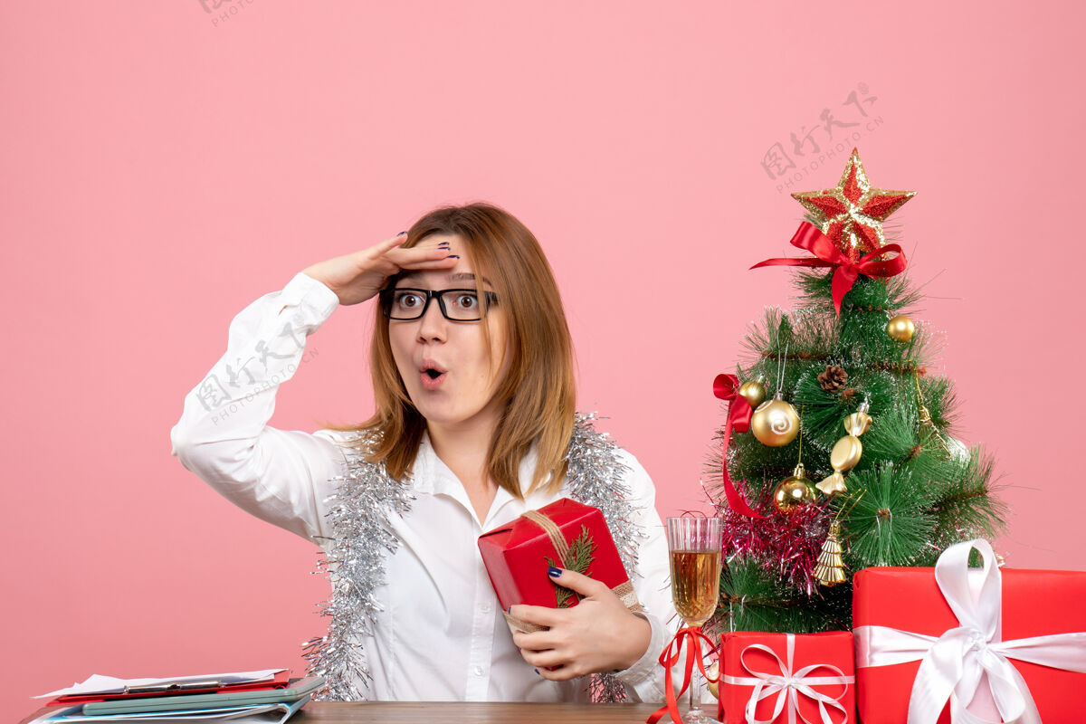工作女工正坐在粉红色的椅子上 手里拿着圣诞礼物工人坐着女性